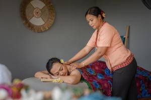 a woman is giving a woman a massage at Dolphin Villa Lovina in Temukus
