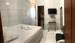 a white room with a bed and a television at Hotel do Hulk in Barreirinhas