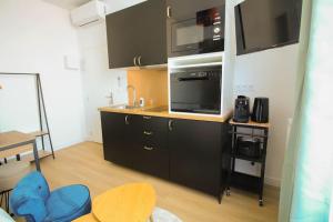 a kitchen with black cabinets and a microwave at G3 Studio Climatisé Centre Angouleme in Angoulême