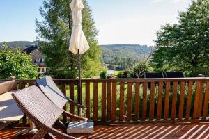 een stoel en een paraplu op een houten terras bij Glück Auf Ferienhäuser Winterberg in Winterberg