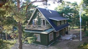 a green house with a blue roof in the woods at Samblatalu Homestay in Laulasmaa +20 photos