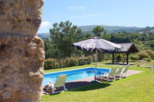 a swimming pool with an umbrella and chairs at Vista Verde Lodge in Vale de Cambra +33 photos