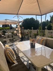 a table and chairs under an umbrella on a patio at Стаи за гости Бела in Ahtopol +16 photos
