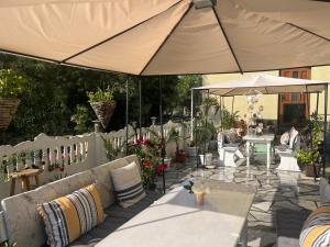 an outdoor patio with tables and umbrellas and plants at Стаи за гости Бела in Ahtopol