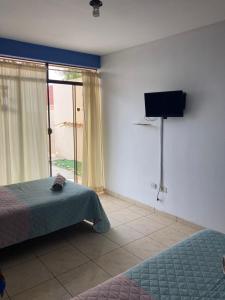 Un dormitorio con dos camas y un televisor de pantalla plana. en Sueños de Chicama, en Puerto Chicama