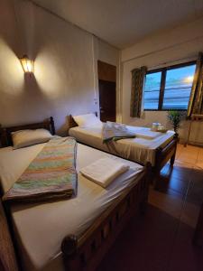 zwei Betten in einem Hotelzimmer mit Fenster in der Unterkunft Yamawa Guest House ยามาวาเกสเฮ้า in Trang