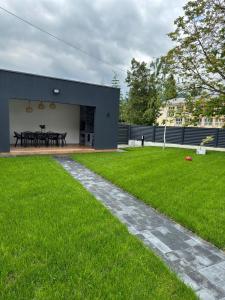 a house with a grassy yard next to a building at Casa de vacanta Cris 2 in Băile Olăneşti