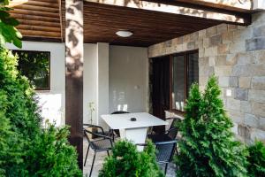 a white table and chairs on a patio with trees at Guesthouse Juli in Sapareva Banya