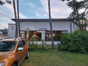 an orange car parked in front of a building at W Sosnach E in Dziwnówek