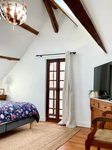 una camera da letto con un letto, una tv e una finestra di La petite Maison en Normandie a Muids