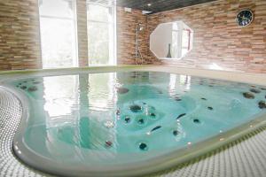 a large jacuzzi tub with blue water in a room at LA MAISON DES CHEVAUX in Eu