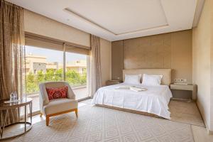 a bedroom with a bed and a chair and a window at ZT 36 by Majestic Properties in Marrakech +43 photos