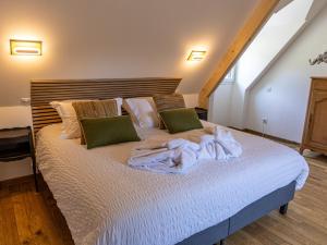 a bedroom with a bed with white sheets and green pillows at Le Domaine d’Angerville - Le Gîte in Dozulé