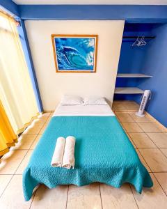Una habitación azul con una cama con dos toallas. en Sueños de Chicama, en Puerto Chicama