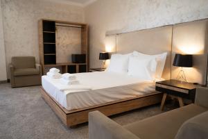 a hotel room with a large bed and a chair at Hotel CITY Sandanski in Sandanski