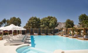 a swimming pool with lounge chairs and an umbrella at Nikki Beach Resort & Spa Santorini in Kamari