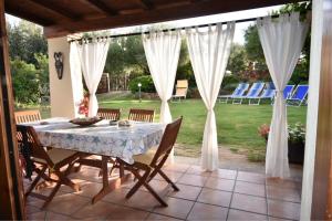 a table and chairs on a patio with white curtains at Villa Giada in Domus de Maria