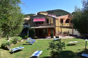 a building with lawn chairs and a house at Villa Giada in Domus de Maria
