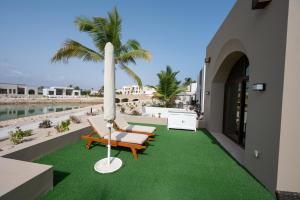 a balcony with a lawn with chairs and an umbrella at Luxury Hawana Villa in Salalah +5 photos