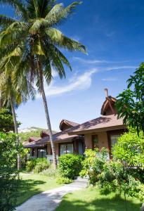 a house with a palm tree in front of it at Maehaad Bay Resort - SHA Plus in Mae Haad