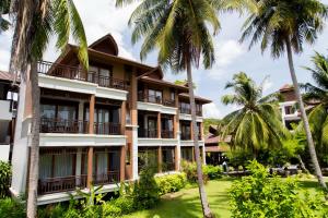 a building with palm trees in front of it at Maehaad Bay Resort - SHA Plus in Mae Haad