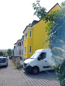 Ein weißer Lieferwagen parkte vor einem gelben Gebäude in der Unterkunft Monteurwohnungen Distelfeld in Saarbrücken