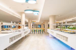 a cafeteria with white counters and tables and food at HOVIMA La Pinta Beachfront Family Hotel in Adeje