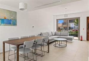Una sala de estar con un sofá, una mesa y sillas. en Serenity Waves Villa 22, en Lárnaca
