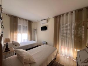 a bedroom with two beds and a tv and a window at Time Holiday´s House in Olhão