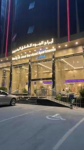 Al Ḩawīyahにあるابراج الجود للشقق المخدومةの建物の前に車が駐車されている