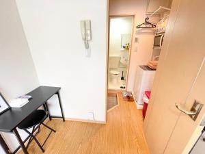 Habitación pequeña con escritorio y nevera. en シャンテ高田馬場11, en Tokio
