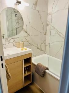 Un baño con lavabo, bañera y espejo. en L'évasion, en Le Barcarès