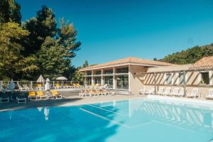 a swimming pool with chairs and a building at Club Vacances Bleues Domaine de Ch&acirc;teau Laval in Gr&eacute;oux-les-Bains