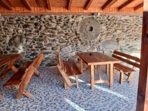 a wooden table and chairs in front of a stone wall at Pensiunea Dateș in Cârțișoara