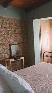 a bedroom with a stone wall with a bed and a mirror at Το Αρχοντικό του Κάστρου in Kyparissia