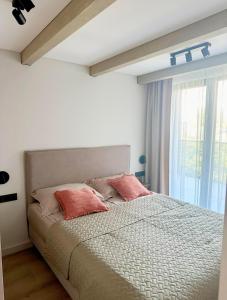 a bedroom with a bed with pink pillows and a window at LEX apartments in Palanga