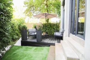 a patio with an umbrella and chairs and a lawn at G7 Loft SPA & Terrasse centre Angouleme in Angoulême