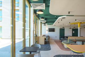 a dining room with tables and chairs and windows at Hôtel AKENA Strasbourg - Hoerdt in Hoerdt