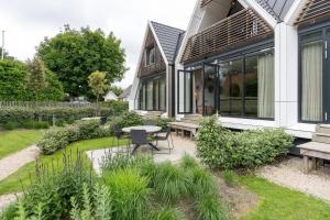 een huis met een patio en een tafel en banken bij NEW! Fantastic appartments - Duno Lodges 4 persons in Oostkapelle