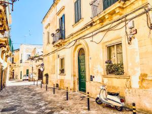 a scooter parked next to a building with a green door at GALA Apartments - Charme Barocco a due passi da Piazza Duomo in Lecce