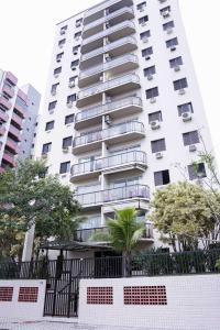 a tall white building with a fence in front of it at Menlia Guarujá in Guarujá