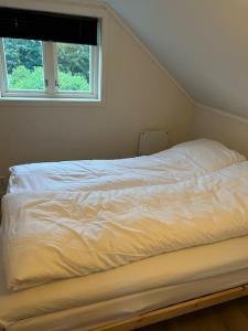 a white bed in a room with a window at Lite hus 15 min fra Oslo in Høvik