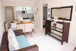 a living room with a couch and a dining room at Menlia Guarujá in Guarujá