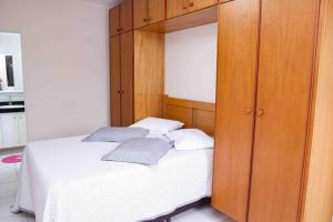 a bedroom with a bed and a wooden cabinet at Menlia Guarujá in Guarujá +40 photos