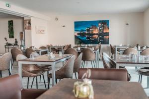 a restaurant with tables and chairs and a painting on the wall at Brit Hotel Confort Saint-Lô in Saint Lo