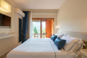 a bedroom with a large white bed with blue pillows at Boutique Hotel Torre Di Cala Piccola in Porto Santo Stefano