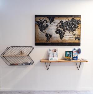 a map of the world hanging on a wall with a shelf at Brit Hotel Confort Saint-Lô in Saint Lo
