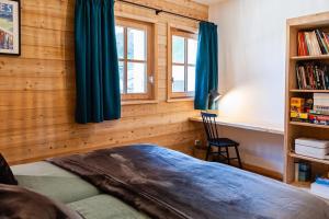 a bedroom with wooden walls and a bed with blue curtains at La Java in Villard-Reculas