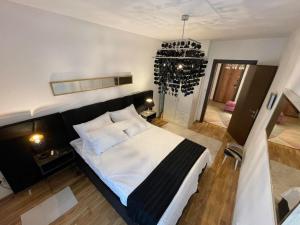 a bedroom with a large bed and a chandelier at Lux Tea Pancevo in Pančevo