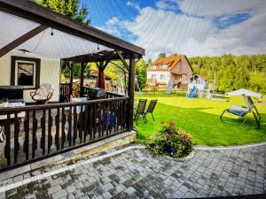 una casa con un porche con un patio y un jardín en Dom na Likusach, en Olsztyn